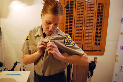 A policewoman fixes her badge on her uniform