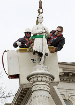 Crews in a crane remove a decrepit Civil War statue from the Muscatine County Courthouse lawn